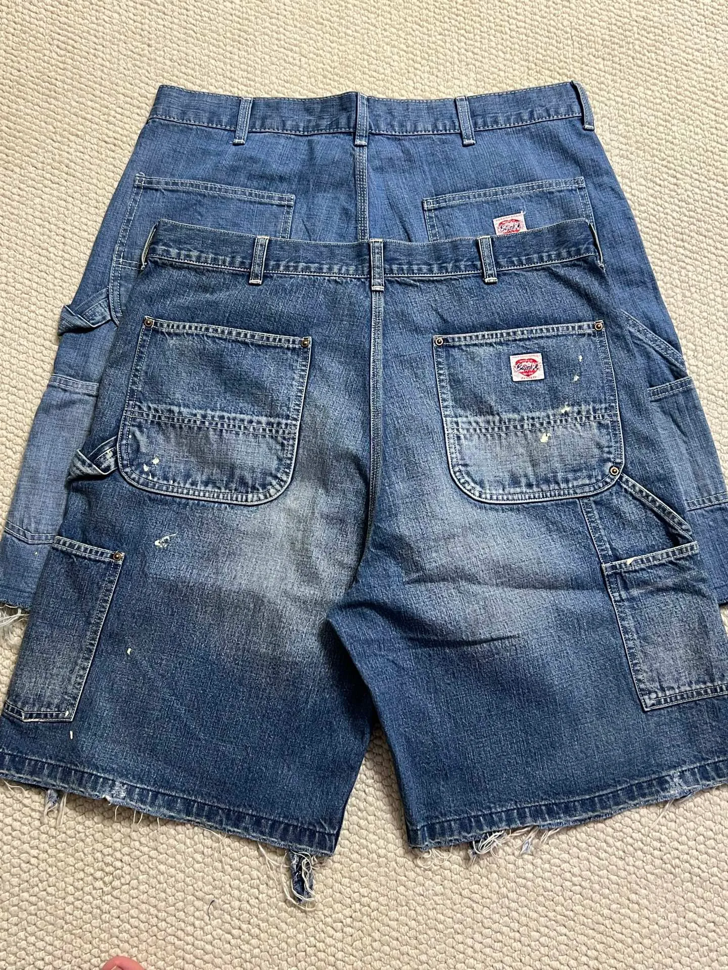 SAINT Mxxxxxx DOUBLE KNEE SHORTS/BLU Knee patches splashed with ink and water-splashed denim shorts. Denim blue S-XL. Custom-woven and dyed denim fabric with clear texture. Heavy-wash water-fading treatment to create local mottled fading/hole effects. Artificial distressing to simulate natural wearing marks. VINTAGE sense. Original consistent damage treatment. Hand-splashed ink and paint. Original consistent wash mark/pocket mark. Double knee patch. Rivet reinforcement. Improve functionality while enhancing design